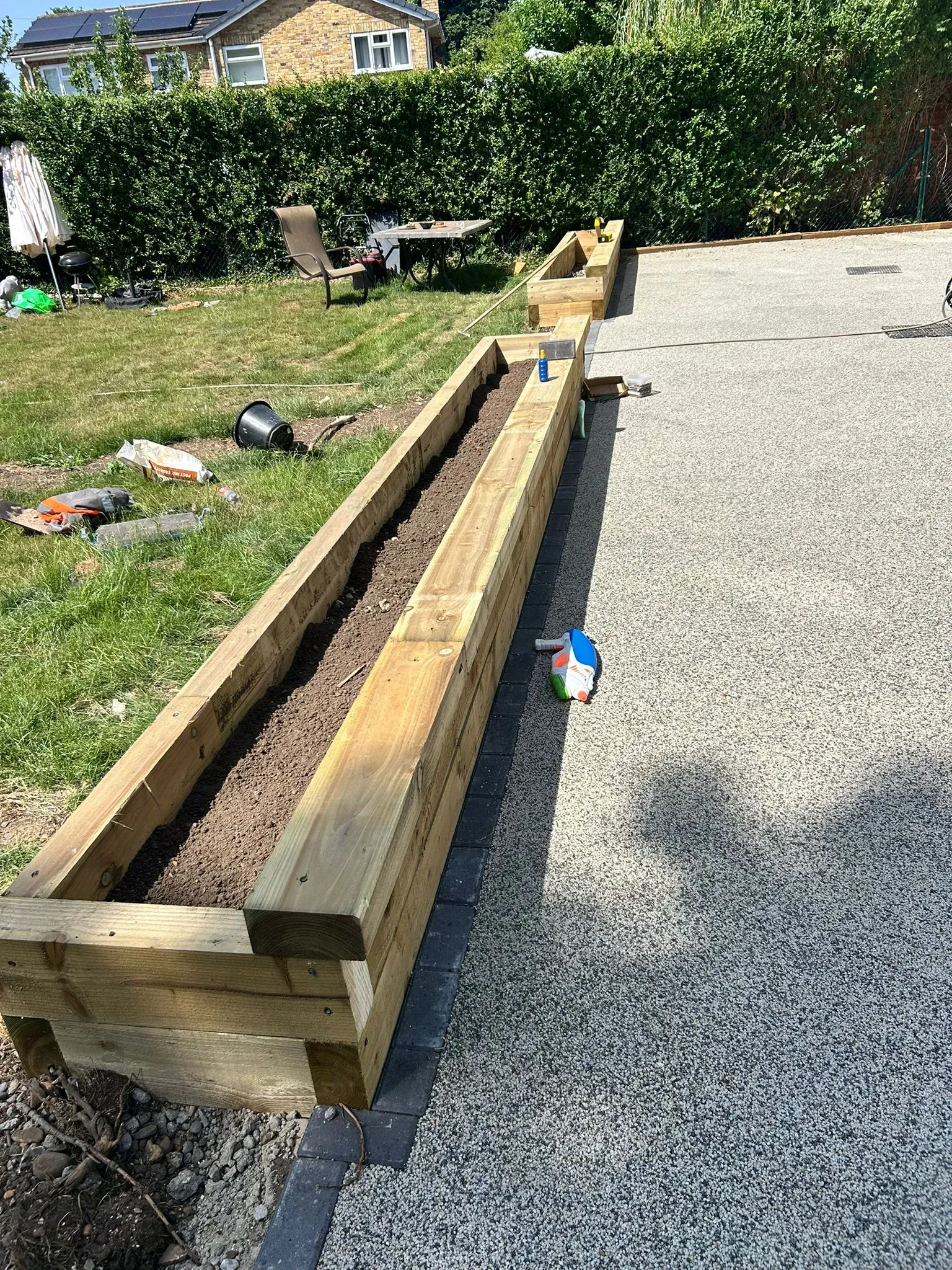 Timber sleeper raised bed planter alongside a resin-bound surface and block paving border