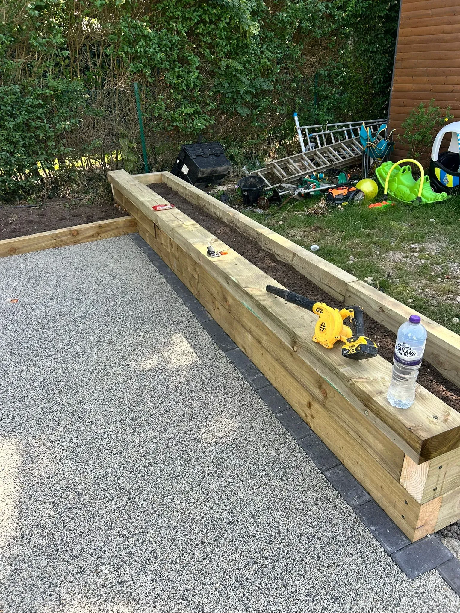 Resin-bound surfacing with block paving edging and timber sleeper raised garden planter installed by River Vale (U.K) Ltd