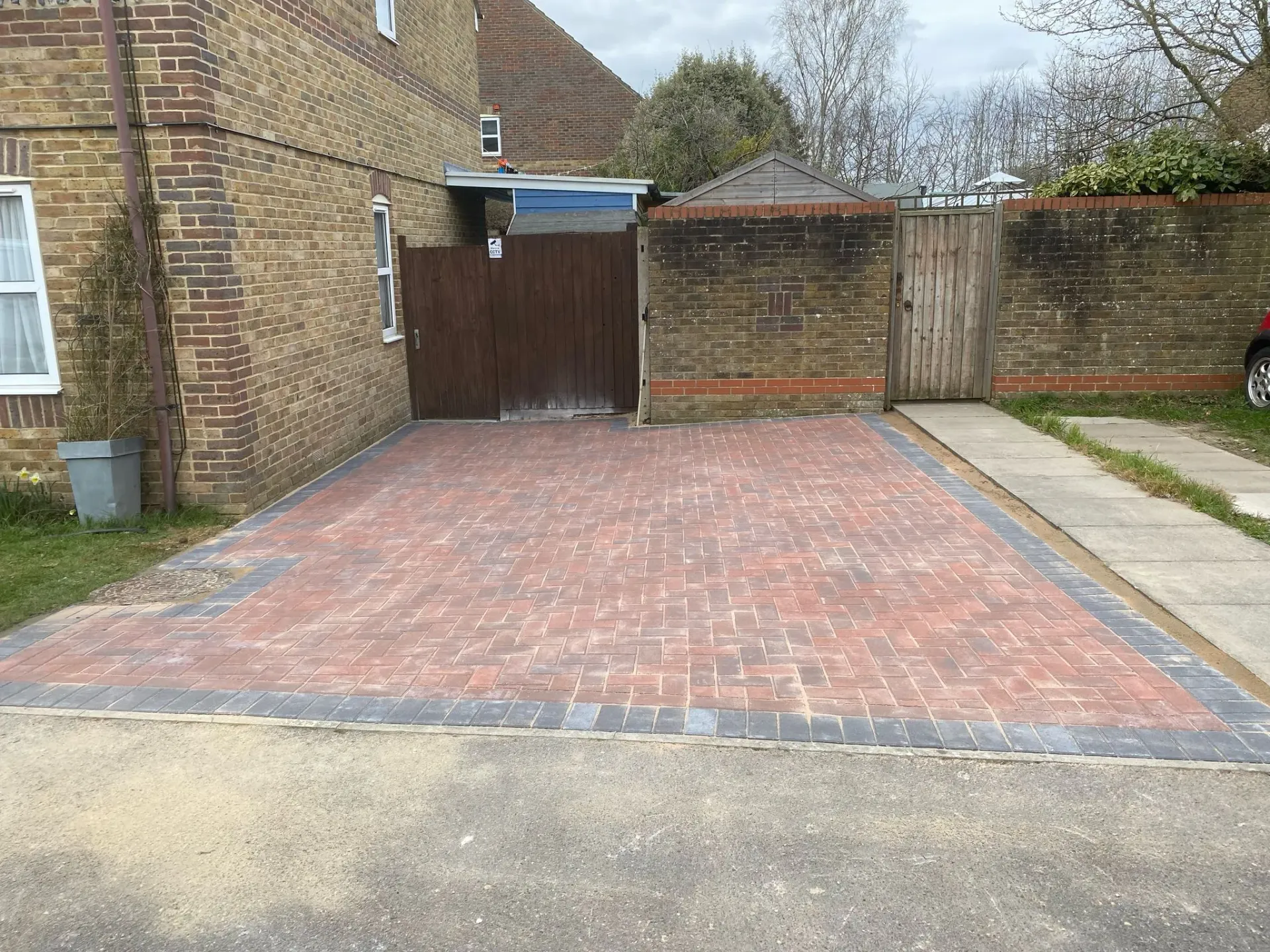 Completed block paving driveway installation with red herringbone paving and charcoal kerb borders
