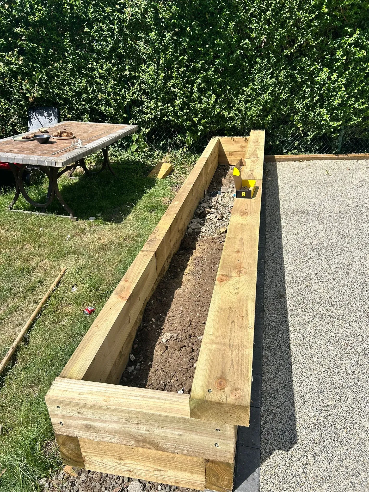 Raised timber sleeper planter bed installed alongside a resin-bound surface during a garden landscaping project