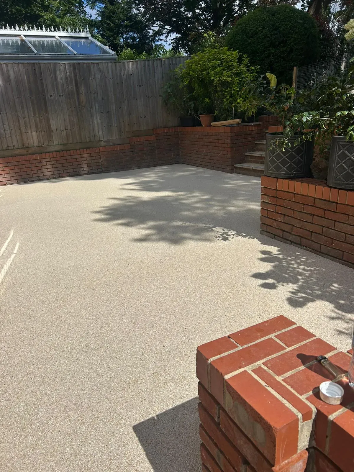 Seamless resin-bound surfacing laid adjacent to red-brick retaining garden walls and timber fencing