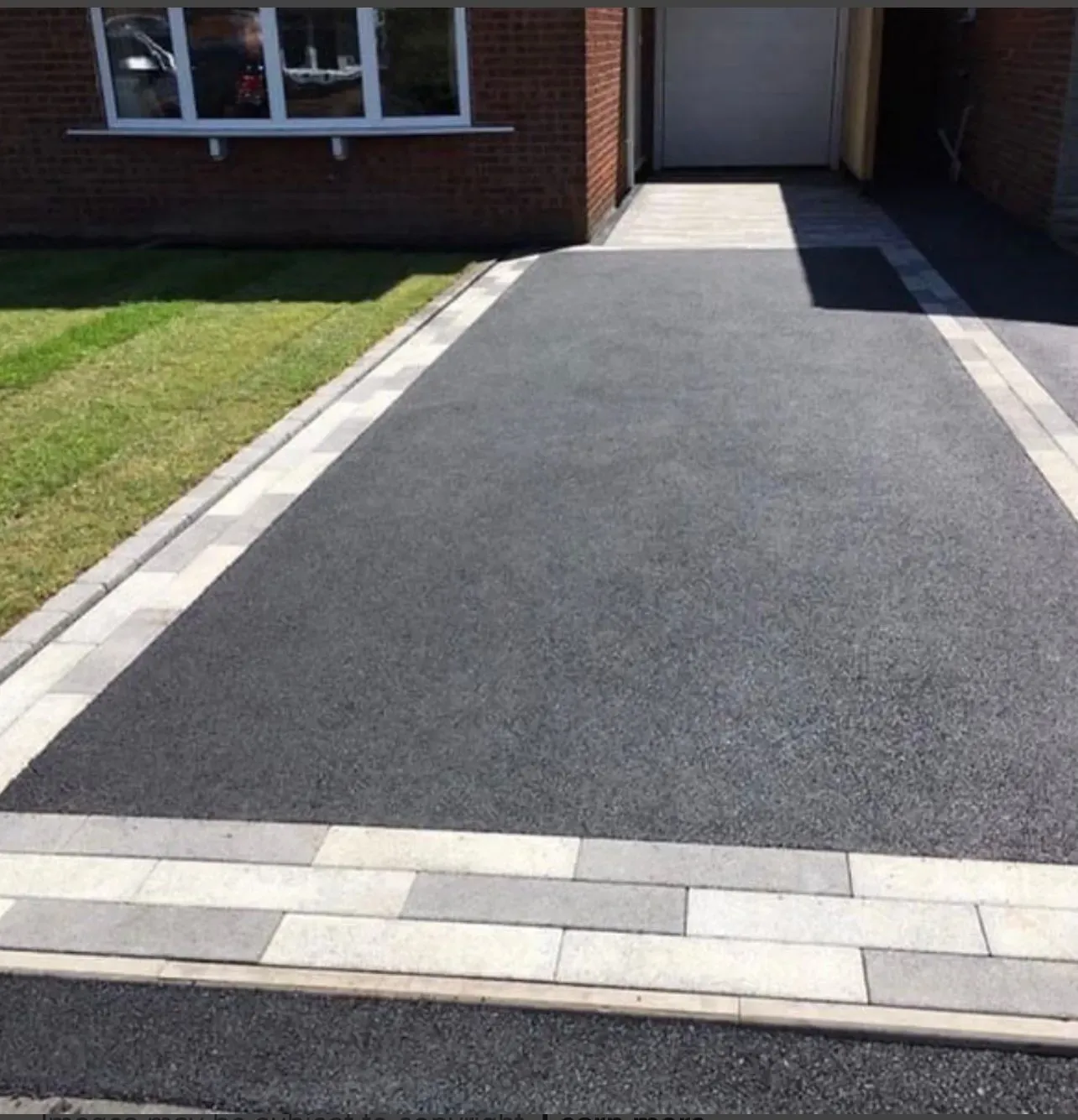 Newly installed tarmac driveway with light grey block paving border edging