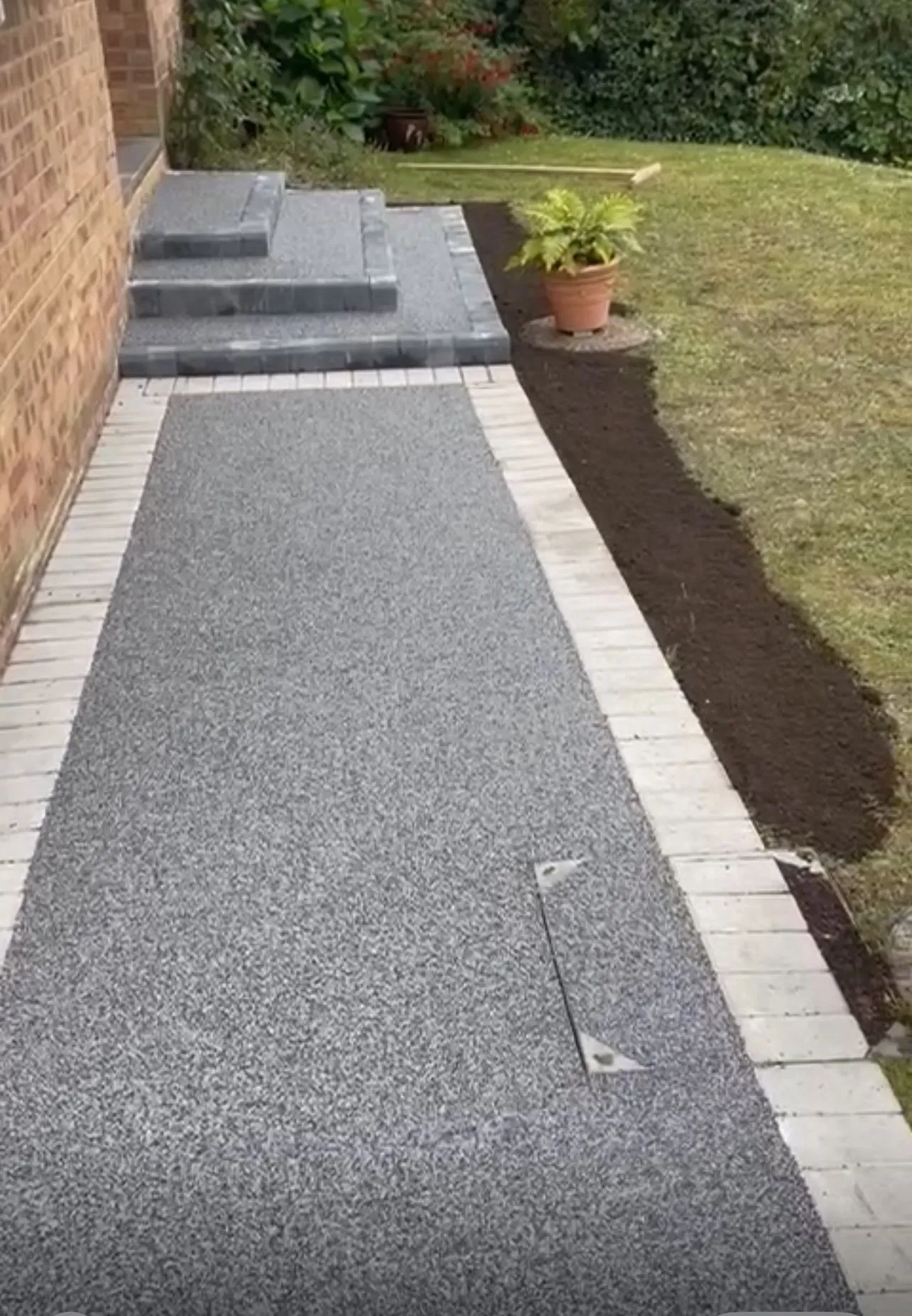Resin bound pathway and entrance steps with block paving edging and recessed manhole cover