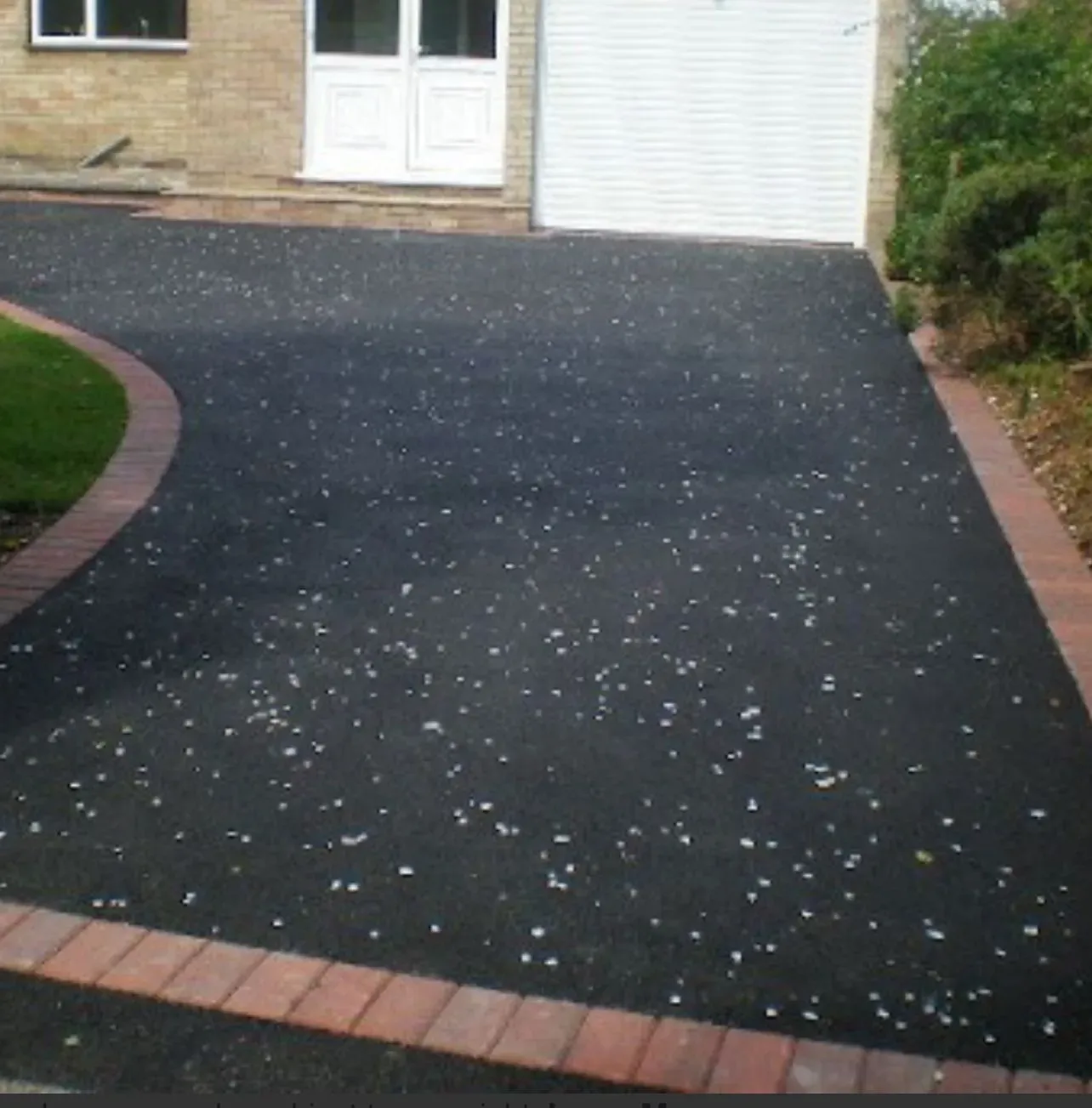 Tarmac driveway installation edged with red block paving border in front of a residential home